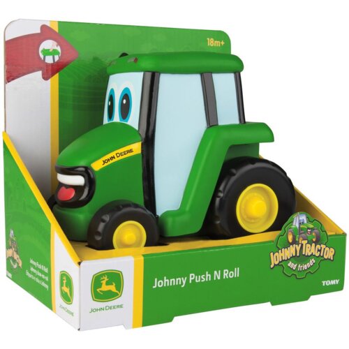 Zabawka w kształcie zielonego traktora z dużymi oczami, umieszczona w opakowaniu z napisem "Johnny Push N Roll" oraz logo "John Deere". Na opakowaniu widnieje również napis "18m+" i logo "TOMY".